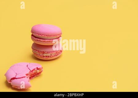 Stapel von rosa Makronen auf gelbem Hintergrund. Bunte Mandelkekse. Pastell Kuchen Macarons Hintergrund mit Kopierraum Stockfoto