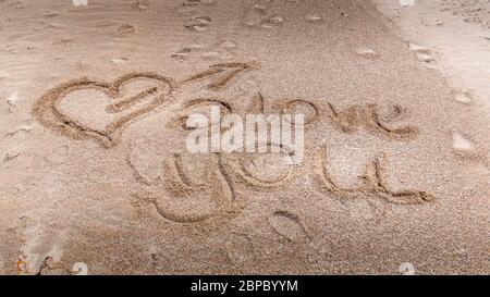 Llove Sie handschriftlich in Sand am Strand. Herz im Sand Stockfoto