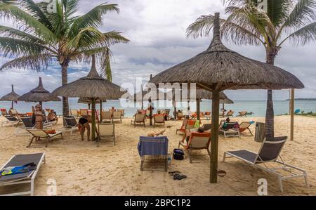 Strohhütten und Relaxliegen am Strand eines tropischen Resorts auf der Insel Mauritius Stockfoto