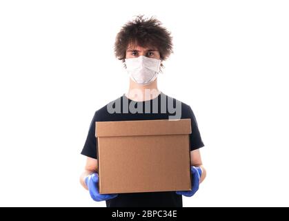 Junger Mann in einer Maske und einem schwarzen T-Shirt und Latexhandschuhe hält einen Karton für Lieferung isoliert auf weißem Hintergrund. Spendenbox. Lieferung Stockfoto