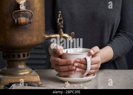 Seitenansicht der weiblichen Hände Gießen Tasse Tee aus Vintage Samowar und Glas hausgemachte Marmelade, Tee Party-Konzept Stockfoto