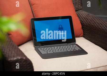 Ein Business-Laptop oder Notebook mit Privatsphäre-Optionen auf dem Bildschirm, der auf einem Korbsessel in einer Außenterrasse ist. Stockfoto