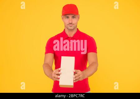 Service plus Qualität. Serious Kerl halten Paket gelben Hintergrund. Man Lieferservice. Express-Kurierdienst. Versand- und Lieferservice. Versand per Paketpost. Wert auf uns verlassen, kopieren Raum. Stockfoto