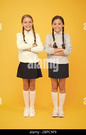 Schließlich absolvierte. Wissen Tag. Kindheit Glück. smart kleinen Mädchen auf gelben Hintergrund. Bildung Konzept. zurück zu Schule. Mädchen in Schuluniform. Kid Mode. Freundschaft und der schwesternschaft. Stockfoto