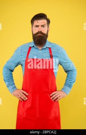 Bärtiger Mann in Koch Uniform. Reifer Verkäufer. Koch in roter Schürze. Restaurantpersonal. Hobby Kochen. Viele Liefertage Optionen. Die ganze Familie würde es genießen. Kochen zu Hause. Hilfe im Haus. Stockfoto