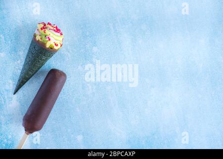 Eis in Schokolade, Eiszapfen mit grüner Waffel und hellen Krümeln. Ein paar Eiscreme auf blauem Hintergrund Stockfoto
