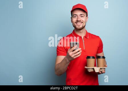 Courier liefert Ihnen gerne heißen Kaffee und Speisen. Cyanfarbener Hintergrund Stockfoto