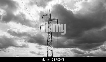 Wolkiger Himmel über einem elektrischen Pylon, monochromes Foto Stockfoto