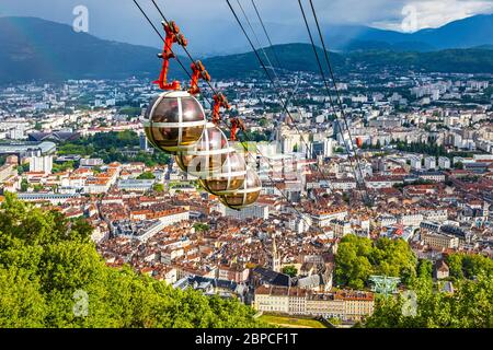 Malerische Luftaufnahme von Grenoble Stadt, Auvergne-Rhone-Alpes Region, Frankreich. Grenoble-Bastille Seilbahn im Vordergrund. Französische Alpen auf dem Rücken Stockfoto