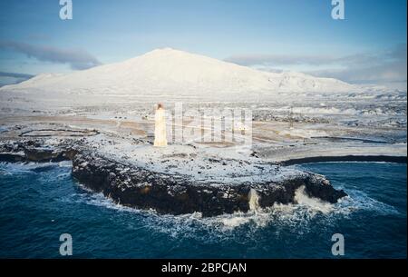 Erstaunliche Drohne Blick auf isländische Landschaft des Leuchtturms und Berggipfel an sonnigen Tag im Winter Stockfoto