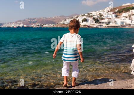 Kleiner Junge in Weiß, der auf Mykonos, Griechenland, unterwegs ist Stockfoto