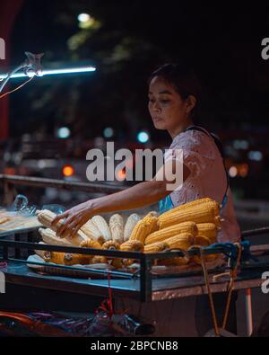 Eine Frau grillen Hühneraugen in Bangkok, Thailand, Thai Street Food Stockfoto