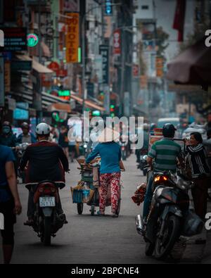 Eine unbekannte Frau verkauft Körbe. Straßenverkauf mit dem Fahrrad oder zu Fuß ist ein wesentlicher Bestandteil des Lebens in Vietnam. Stockfoto