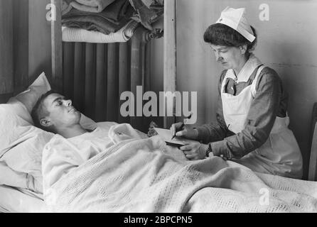 Krankenschwester schreibt einen Brief nach Hause für einen verwundeten amerikanischen Soldaten im American Military Hospital No. 1, Neuilly, Frankreich, Lewis Wickes Hine, American National Red Cross Photograph Collection, Juni 1918 Stockfoto