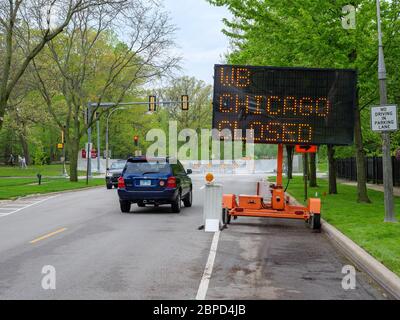 River Forest, Illinois, USA. Mai 2020. Elektronisches Umleitungsschild leitet den Verkehr von der Chicago Avenue Brücke über den des Plaines River weg. Die Straße war wegen Brückenarbeiten gesperrt worden, aber der Fluss überflutete nach heftigen Regenfällen, so dass eine temporäre Hochwasserbarriere gebaut werden musste, die im Hintergrund zu sehen war. Stockfoto