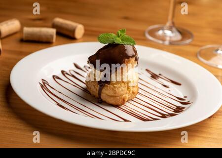 Profiteroles gefüllt mit Vanilleeis auf weißem Teller Stockfoto
