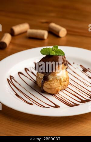 Profiteroles gefüllt mit Vanilleeis auf weißem Teller Stockfoto