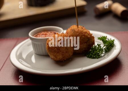 Arancini italienische Risotto-Kugeln gefüllt mit Mozzarella-Käse, Tomaten-würzige Sauce auf einem verschwommenen dunklen Hintergrund Stockfoto