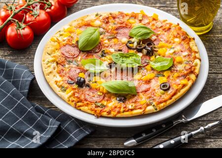 Leckere Salami-Pizza. Pizza mit Basilikumblättern auf dem Teller. Stockfoto