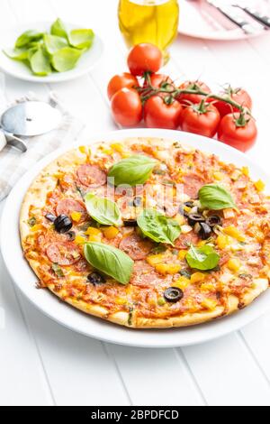 Leckere Salami-Pizza. Pizza mit Basilikumblättern auf dem Teller. Stockfoto
