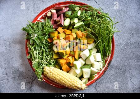 Kürbis, Zucchini, Thymian, Ocimum Basilicum, Chaam, Okra, Süßer Mais im Tablett auf dunklem Hintergrund. Gemischte Gemüsezutaten im nordöstlichen Foo Stockfoto