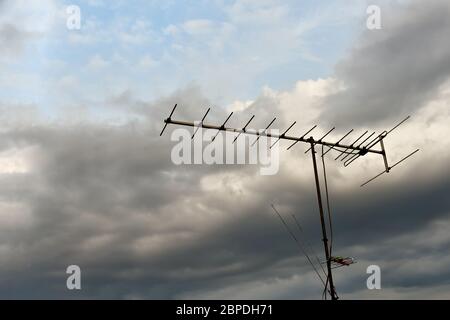 Alte Fernsehantenne oder Fernsehantenne auf einem Hintergrund wolkiger Himmel Dunkle starke Gewitterwolken vor Regen. Konzept eines Gewitters oder eines Dangerou Stockfoto