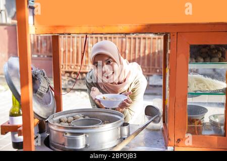 Schöne asiatische Frau muslim Kunde kaufen Bakso Stockfoto