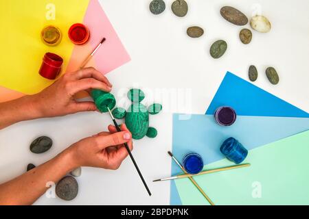 Schritt für Schritt eine Steinschildkröte auf einem Stein malen. Kinder Kunstprojekt. DIY-Konzept. Schritt für Schritt 3 Fotoanleitung.Ansicht von oben. Arbeiten mit c Stockfoto
