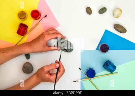 Wie man einen Regenbogen auf einem Stein Schritt für Schritt zeichnet. Kinder Kunstprojekt. DIY-Konzept. Schritt für Schritt Fotoanleitung.Ansicht von oben. Mit Kindern arbeiten A Stockfoto