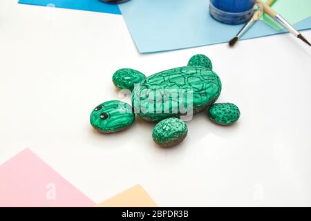 Schritt für Schritt eine Steinschildkröte auf einem Stein malen. Kinder Kunstprojekt. DIY-Konzept. Schritt für Schritt Fotoanleitung.Ansicht von oben. Arbeiten Sie mit Chi Stockfoto