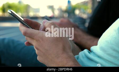 Männer, die ihre Mobiltelefone auf einer Bank benutzen. Stockfoto