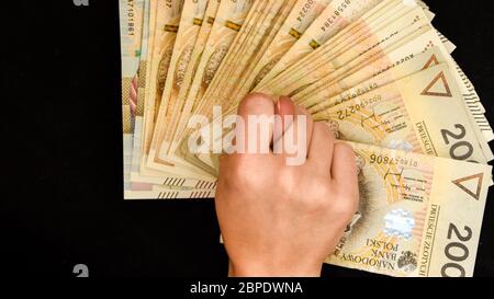 Hand in Hand mit polnischem Zloty isoliert auf schwarzem Hintergrund, Hand mit polnischem Zloty, Trading Business Theme, zweihundert Geldscheine Stockfoto