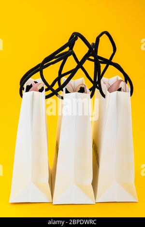 Set mit weißen Papiertüten zum Einkaufen auf gelbem Hintergrund. Mockup für Design, Platz für Kopien, Einkaufstaschen und Platz für Kopien für Klartext oder Produkt Stockfoto