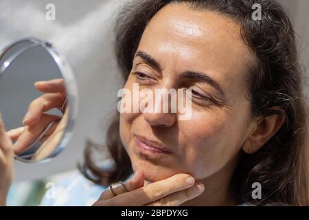 Hübsche junge hispanische Frau reinigt ihre Augenbrauen Stockfoto