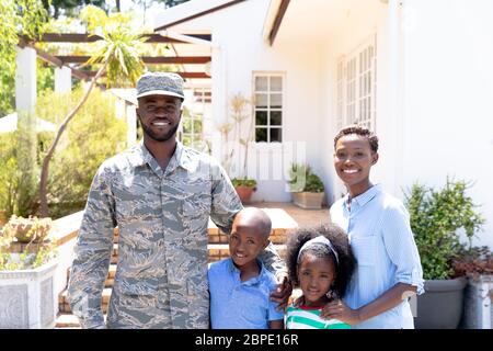 Afroamerikanischer Soldat in Uniform und seine Familie steht bei ihrem Haus Stockfoto