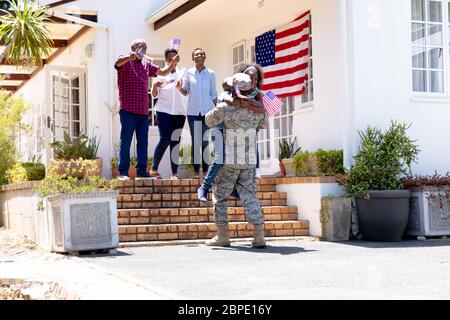 Afroamerikanischer Soldat in Uniform und seine Familie steht bei ihrem Haus Stockfoto