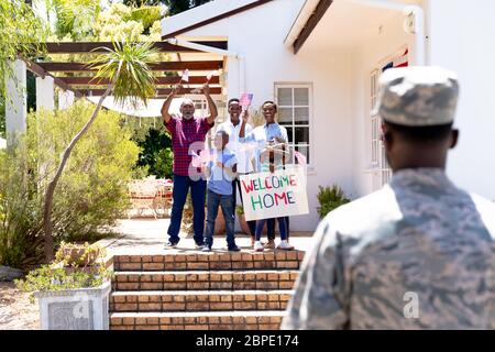 Afroamerikanischer Soldat in Uniform und seine Familie steht bei ihrem Haus Stockfoto