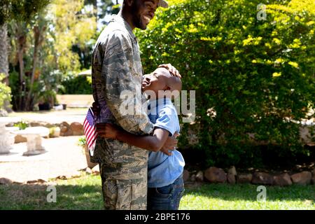 Afroamerikanischer Soldat umarmt seinen Sohn mit einer US-Flagge Stockfoto