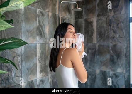 Brünette Frau in der Dusche im Nachtschleid stehen, wischen ihr Gesicht mit Handtuch Stockfoto