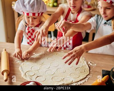 Drei kleine Köche genießen in der Küche Kuchen zu machen. Mädchen in der Küche. Haushaltung für Familien. Stockfoto