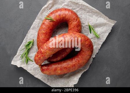Geräucherte Wurst mit Rosmarin auf schwarzem Schiefergrund. Draufsicht. Flaches Lay. Stockfoto