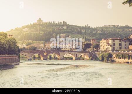 Panoramablick auf die Brücke Ponte Pietra auf Etsch und alte europäische italienische Häuser, beleuchtet von Sonnenuntergang Licht in Verona, Venetien Region, Norther Stockfoto