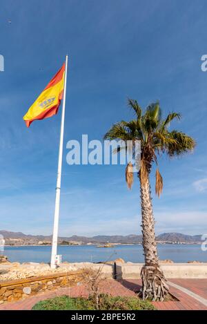 Spanische Flagge am Eingang zum Yachthafen in Puerto de Mazarron, Region Murcia, Costa Calida, Spanien. Palme. Küste in blauem Himmel auf Mittelmeer Stockfoto