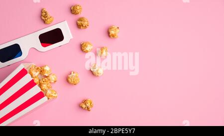 Popcorn Eimer und 3d-Brille auf rosa Hintergrund mit Kopierraum. Filme im Kino online zu Hause ansehen Stockfoto