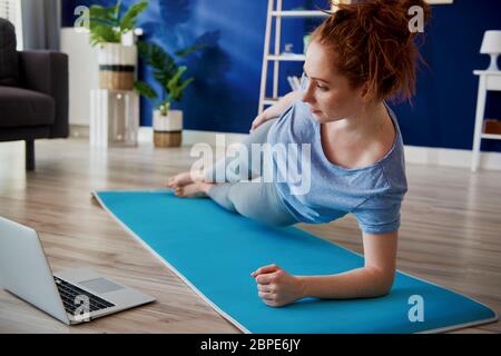 Junge Frau versucht, zu Hause Sport zu treiben Stockfoto