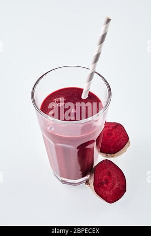 Eine Ansicht von oben nach unten rot Wurzelgemüse Smoothie in einem Glas neben zwei Stücke schneiden Zuckerrüben auf weißem Hintergrund Stockfoto