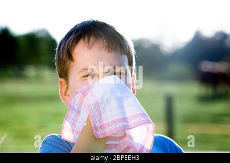 Kind mit einer Allergie gegen Pollen, während Sie Ihre Nase mit einem weißen Taschentuch, in der Natur schneuzen Stockfoto