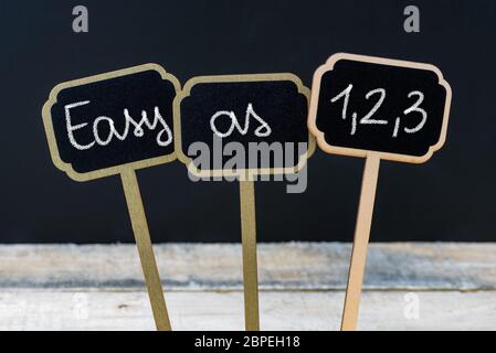 Konzept Nachricht EINFACH WIE 1,2,3 mit Kreide auf Holz mini Blackboard Labels geschrieben, defokussierten Schiefertafel und Holz Tisch im Hintergrund Stockfoto