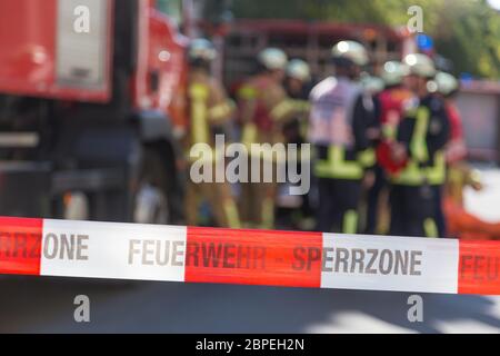 Team von blured Feuerwehrmänner, die durch firetruck auf geschützten Unfallstelle. Fokus auf roten und weißen Sicherheit band. Stockfoto