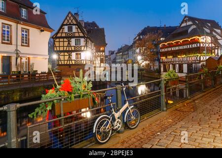 Traditionelle elsässische Fachwerkhäuser mit Spiegelreflexen in Petite France während der Abenddämmerung blaue Stunde dekoriert und beleuchtet zu weihnachten ti Stockfoto